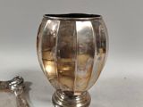 a silver vase sitting next to a mirror on a table