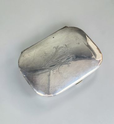 un étui à cigarettes en argent posé sur une surface blanche