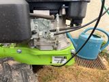 a green lawn mower that is parked next to a blue watering can