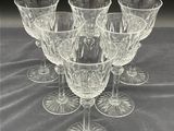 six clear wine glasses sitting on top of a table next to each other