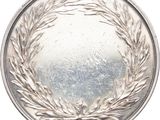 an image of a silver medal with a laurel wreath on it