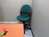 un bureau avec une chaise verte et une chaise rose dans un coin de la pièce