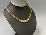 a gold chain necklace on a black mannequin