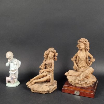 three figurines of a woman and a child on a rock