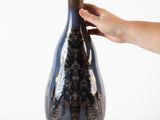 a person holding a vase in their hand on a white background