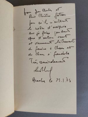 un livre ouvert, sur lequel est posée une note manuscrite, posé sur une table