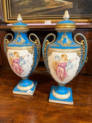 une paire de vases bleus et blancs posés sur une table, avec un tableau en arrière-plan