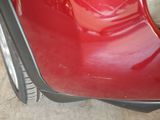 a close up of a red car ' s bumper and tire
