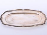 une assiette ancienne en argent, avec un bord décoré sur fond blanc