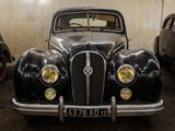 several old cars are parked in a garage with a wall in the background