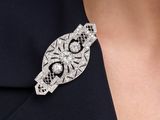 a close up of a woman wearing a black dress and a silver broochle