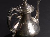 a silver tea pot sitting on a black surface