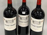 trois bouteilles de vin rouge sont alignées sur une surface blanche