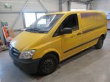 une camionnette jaune garée dans un garage, avec d'autres véhicules en arrière-plan
