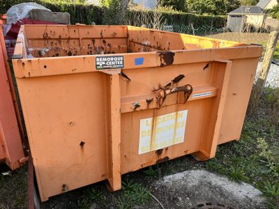 a dumpster sitting in the grass next to a fence