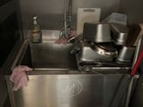 a sink in the kitchen with a lot of clutter on it