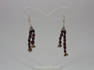 a pair of earrings with red beads hanging from them on a stand