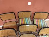 Dans une pièce, plusieurs chaises sont alignées contre un mur rose