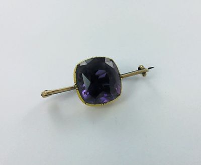 a close up of a purple stone on a gold plated pin