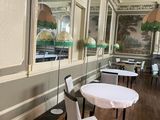 tables and chairs are set up in a room with a painting on the wall