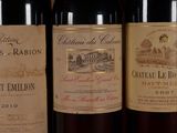 three bottles of red wine are lined up on a shelf