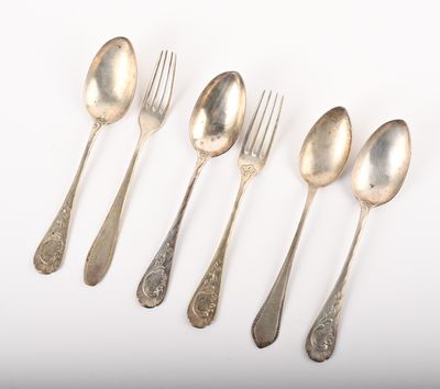 six cuillères et une fourchette sont alignées sur une surface blanche