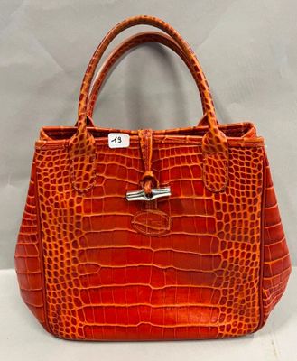 un sac à main en peau de crocodile orange sur fond blanc