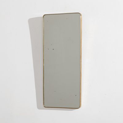 miroir accroché à un mur blanc, avec un cadre doré et un fond blanc
