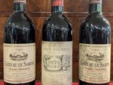 three bottles of wine are lined up on a red cloth