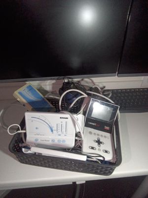 un panier rempli d'appareils électroniques posé sur un bureau où se trouve un écran d'ordinateur