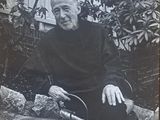 black and white photograph of a man sitting on a bench in front of a tree