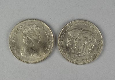 two silver coins sitting next to each other on a white surface