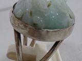 a ring with a green stone in it on a stand
