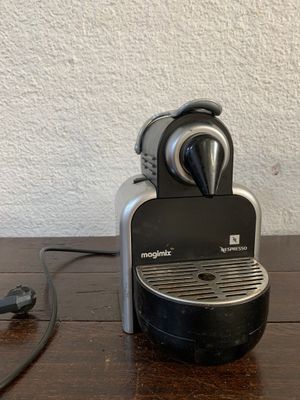 une cafetière posée sur une table, avec un cordon d'alimentation qui y est relié