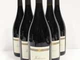 six bottles of red wine are lined up on a white surface