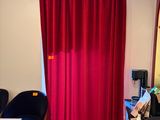 un rideau rouge dans un coin de la pièce, à côté d'un bureau