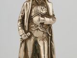 silver figurine of a man wearing a hat and coat