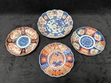 quatre assiettes ornées de motifs différents, posées sur une surface noire