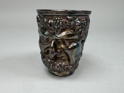 a silver vase with a face on it