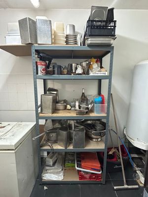 a small kitchen with a lot of clutter on the shelves