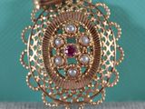une photo en gros plan d'une broche ornée de perles