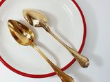 a red and white plate with two gold spoons on it