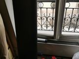 une enceinte noire posée par terre près d'une fenêtre