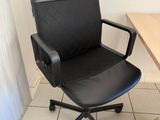 a black office chair sitting in front of a computer desk