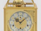a gold clock with a glass dome on top of it