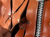 a person holding a brown leather jacket with a zipper