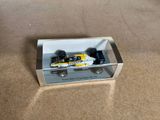 une petite voiture miniature dans une boîte transparente posée par terre