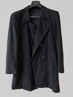 a black jacket hanging on a hanger on a white wall