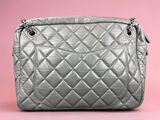 a close up of a silver quilted purse on a pink background