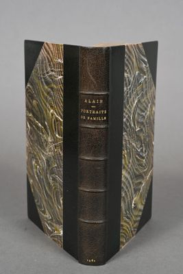an old book with a black cover sitting on top of a table